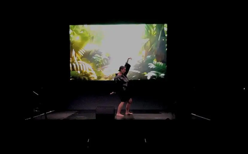 Butoh Dancer performing on a stage in front of 4K generative AI audio-visual work titled: &ldquo;MYCELIO&rdquo;.