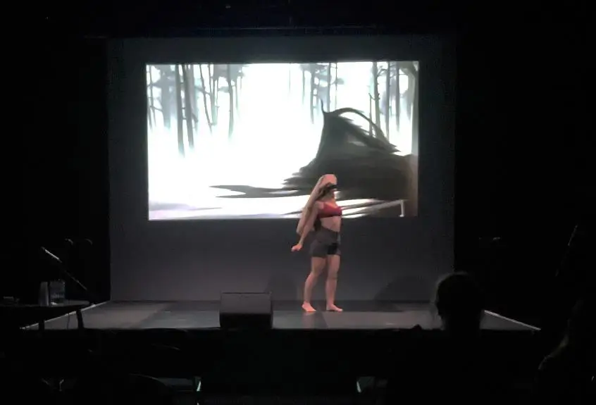 Butoh Dancer performing on a stage in front of 4K generative AI audio-visual work titled: &ldquo;MYCELIO".