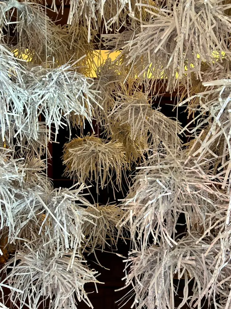 Installation view of &ldquo;Sensing Theory &ndash; Shredding Cognitive Overload.&rdquo; Close-up of several bundles of shredded paper tied together and suspended vertically on strings.