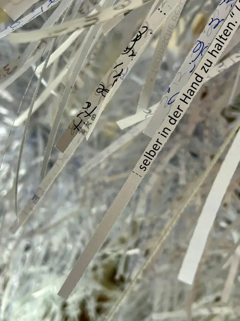 nstallation view of &ldquo;Sensing Theory &ndash; Shredding Cognitive Overload.&rdquo; Detailed view of single paper strips with handwritten notes and typed text fragments, including the words &ldquo;to hold in one&rsquo;s own hands.&rdquo; in German.