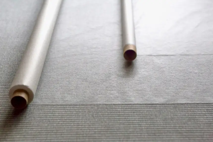 Two rolls of ultra-thin washi paper lying on a Japanese tatami floor, with the floor&rsquo;s texture visible through the translucent paper.