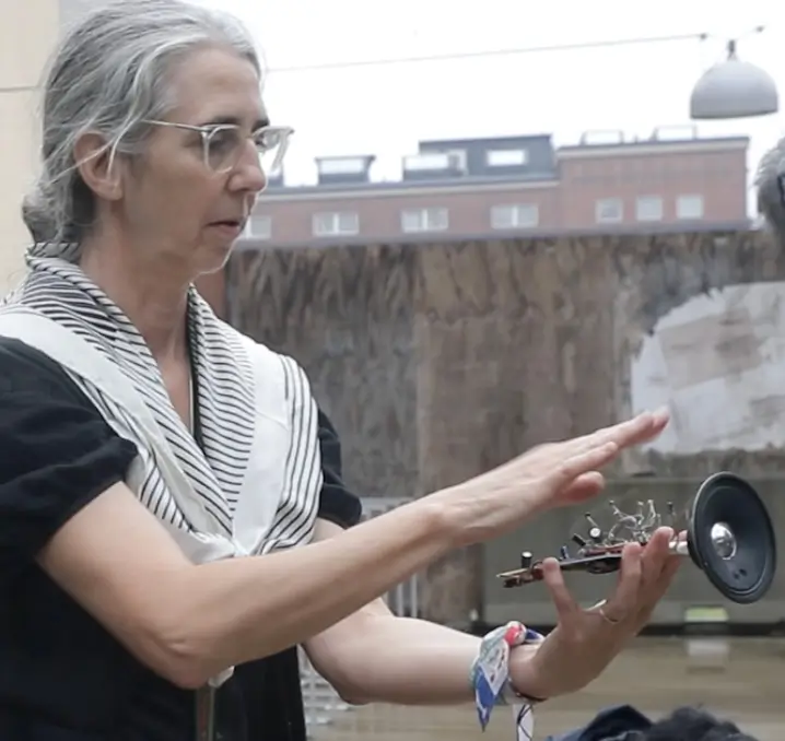 Close-up of Marianne Decoster-Taivalkoski playing the Solar Trumpet in the courtyard.
